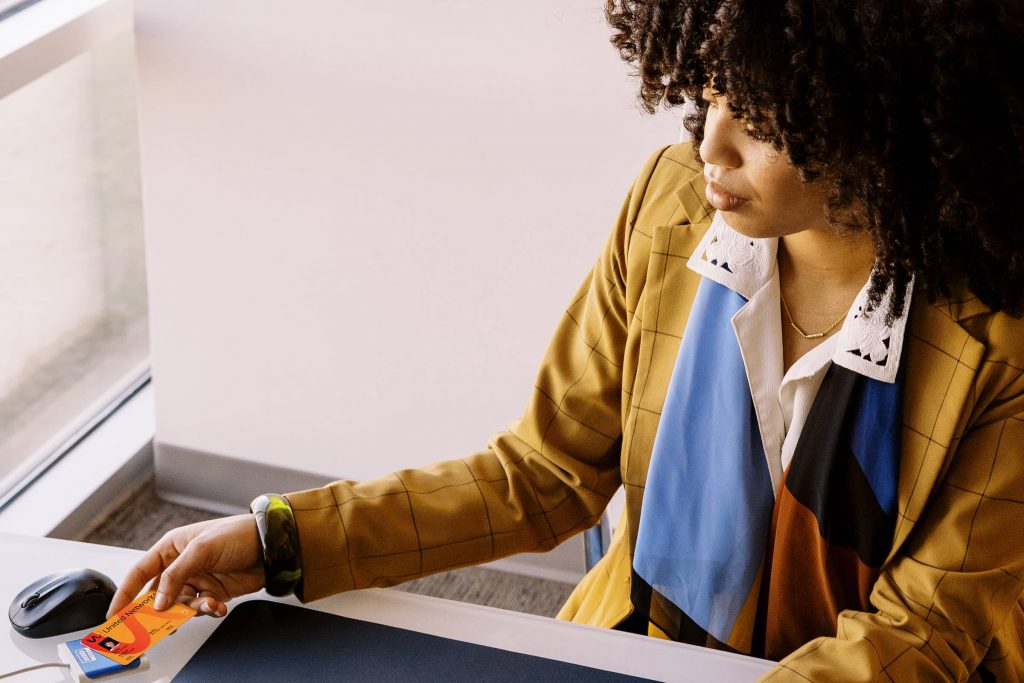 A person sitting at their desk, holding their smart card up to the sensor that's wired to their laptop. This is to authenticate their identity.